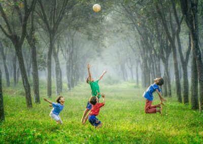 four boy playing ball on green grass